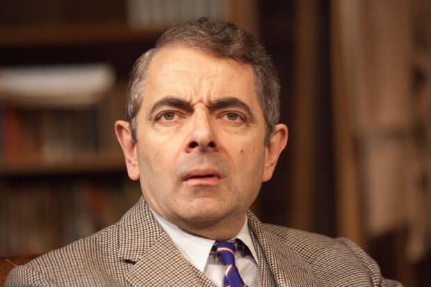 Rowan Atkinson wallpapers shows a close up of a man with a serious expression in a patterned suit, HD Desktop Wallpaper