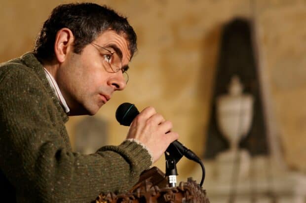 Rowan Atkinson is speaking into a microphone during an event, 2K Desktop Wallpaper