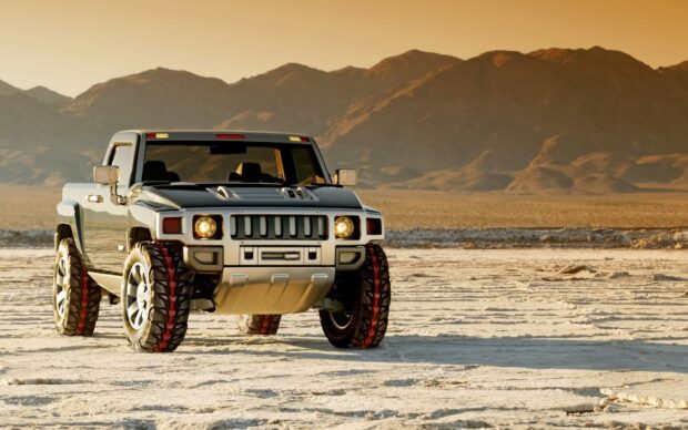 A Hummer H3 is parked on a dry desert floor with mountains in the background under a clear sky, HD Desktop Wallpaper