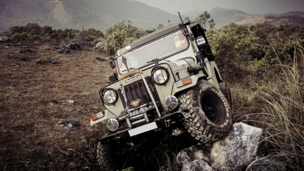 A rugged off road driving vehicle climbs over rocks in a mountainous landscape, 4K Desktop Wallpaper