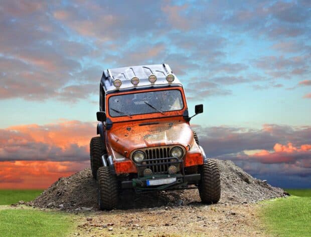 An orange jeep is climbing a dirt mound during off road driving wallpapers under a colorful sky, HD Desktop Wallpaper