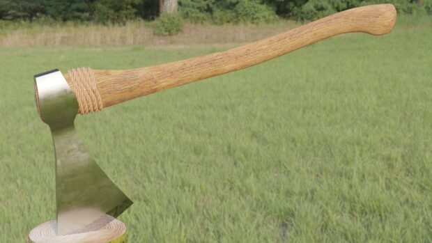 A close up of a rustic axe resting on a piece of wood in a green grassy field with trees, HD Desktop Wallpaper