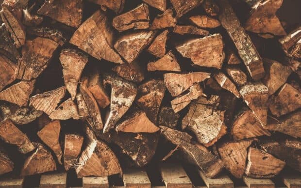 Rustic firewood pile neatly stacked on wooden pallets for lumberjack use, HD Desktop Wallpaper