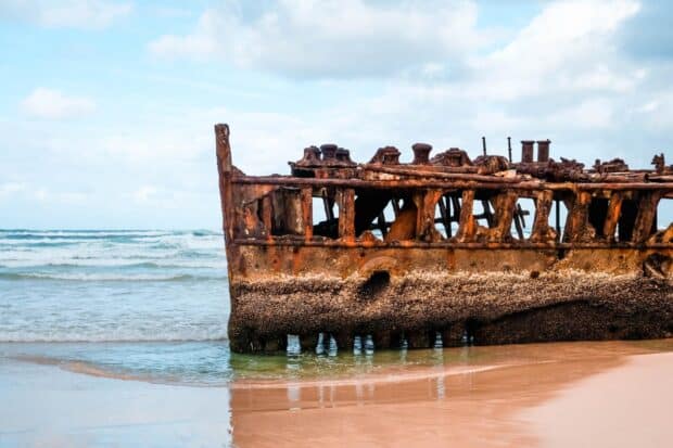 A rusty shipwreck on Fraser Island beach with ocean waves in the background, HD Desktop Wallpaper