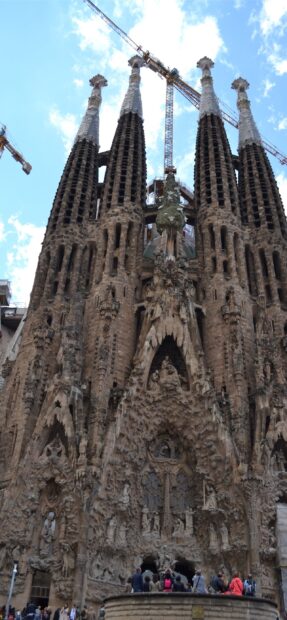 The Sagrada Familia features intricate stone carvings and tall spires under a bright sky, 2K Phone Wallpaper