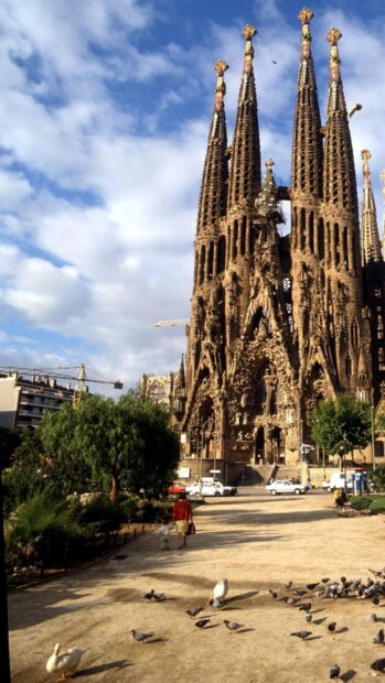 A woman and child walk near the Sagrada Familia with birds and trees around, HD Phone Wallpaper