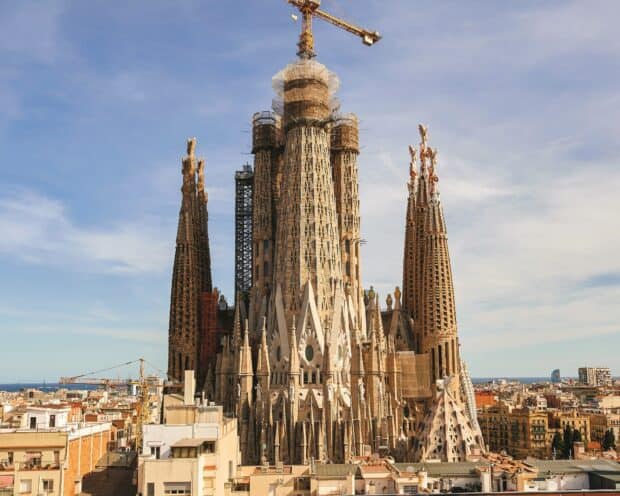 The Sagrada Familia cathedral stands tall with detailed spires against a clear blue sky, HD Desktop Wallpaper
