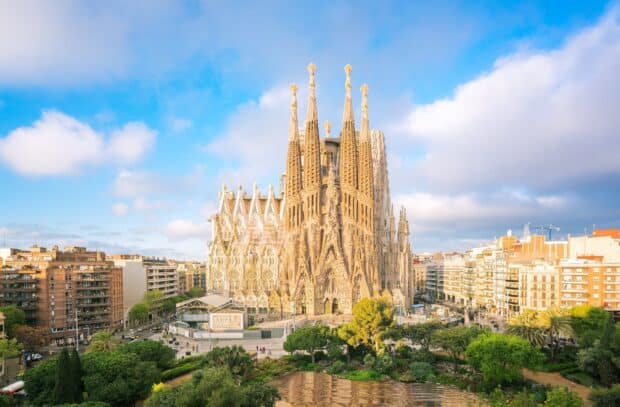 The Sagrada Familia stands prominently amid city buildings under a partly cloudy sky, HD Desktop Wallpaper