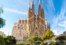 The Sagrada Familia stands tall with intricate details under a blue sky, 2K Desktop Wallpaper