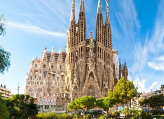 The Sagrada Familia stands tall with intricate details under a blue sky, 2K Desktop Wallpaper