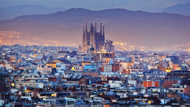 The Sagrada Familia towers over the cityscape with mountains in the background at twilight, 4K Desktop Wallpaper