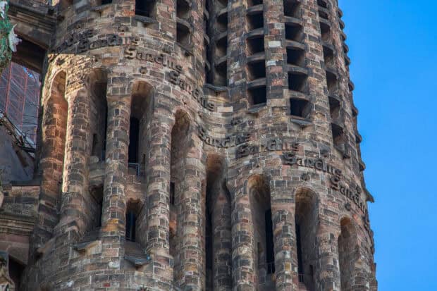 The Sagrada Familia detailed tower features multiple arches and a clear blue sky, 2K Desktop Wallpaper