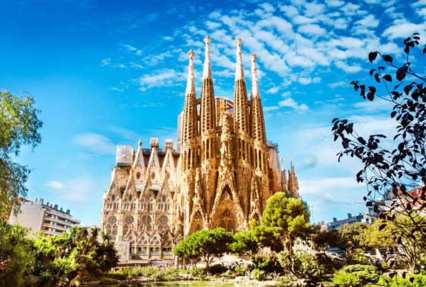 The Sagrada Familia is a famous basilica with detailed spires under a bright blue sky, 2K Desktop Wallpaper