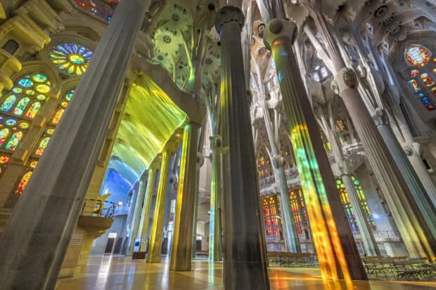 The Sagrada Familia interior shows colorful light reflections on tall columns, 2K Desktop Wallpaper