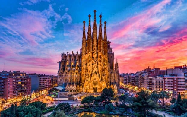 The Sagrada Familia stands illuminated under a colorful sunset sky in Barcelona, 2K Desktop Wallpaper
