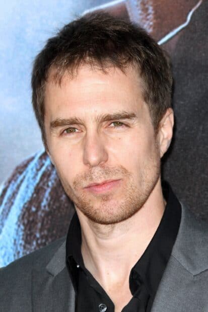 Sam Rockwell close up portrait with brown hair and stubble against blue background, 2K Desktop Wallpaper