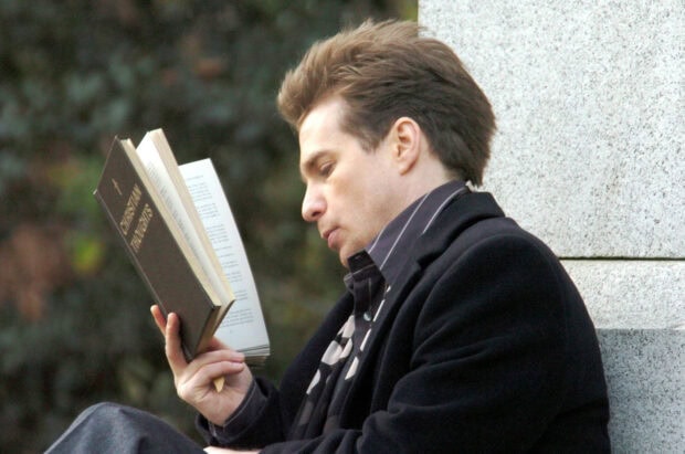 Sam Rockwell reading a book titled Christian Thoughts against a stone wall, HD Desktop Wallpaper