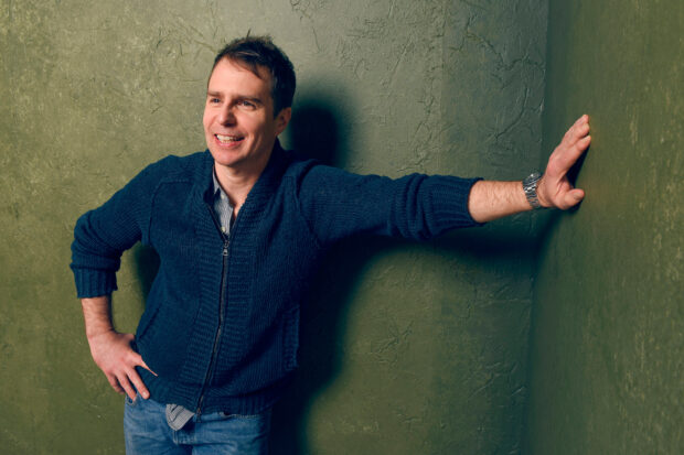 Sam Rockwell smiling casually while leaning against a textured wall, HD Desktop Wallpaper