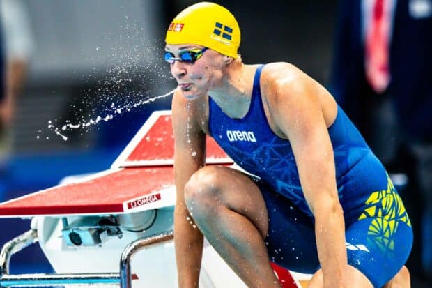 Sarah Sjostrom is crouched at the pool edge wearing a yellow cap and blue suit, HD Desktop Wallpaper