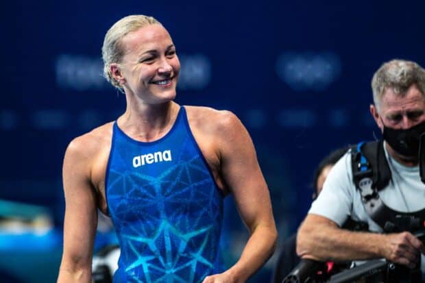 Sarah Sjostrom is smiling and standing in a blue swimsuit at a swimming event, HD Desktop Wallpaper