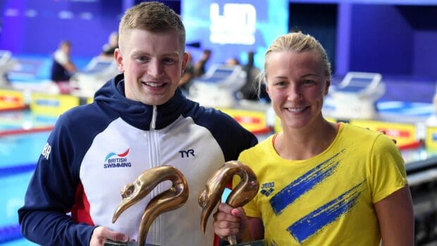 Sarah Sjostrom celebrates with another swimmer holding awards at a swimming event, 2K Desktop Wallpaper