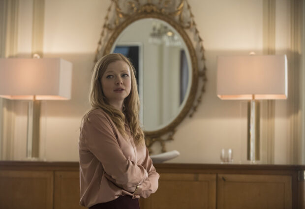 Sarah Snook stands in an elegant room with a decorative mirror and lamps, 2K Desktop Wallpaper