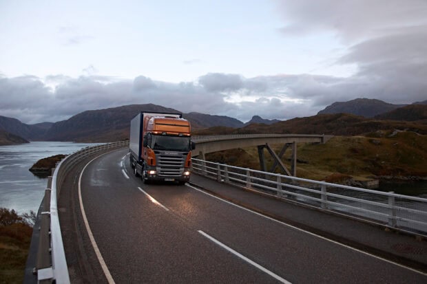 A Scania truck is driving on a curved mountain road under cloudy skies, HD Desktop Wallpaper