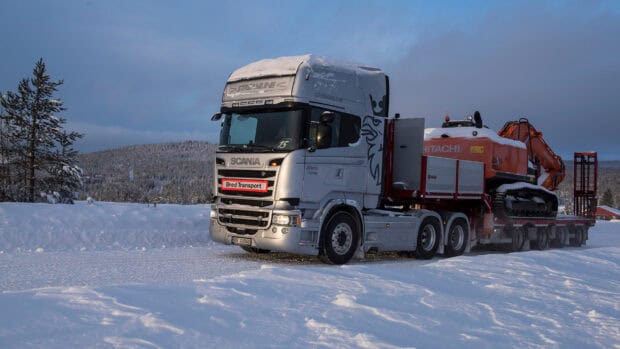 A Scania truck carries heavy construction equipment through a snowy landscape, 2K Desktop Wallpaper