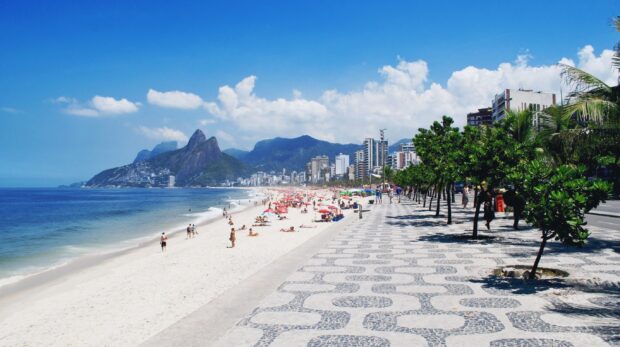People enjoying the sunny Rio de Janeiro beach with mountains and city skyline, 2K Desktop Wallpaper