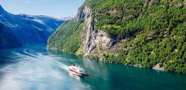 A cruise ship sails through the calm waters surrounded by steep cliffs in the Norwegian fjords, 2K Desktop Wallpaper