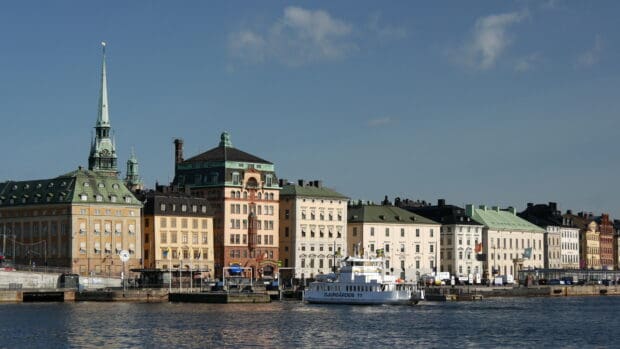 A ferry sails by beautiful historic buildings under a clear blue sky, 4K Desktop Wallpaper