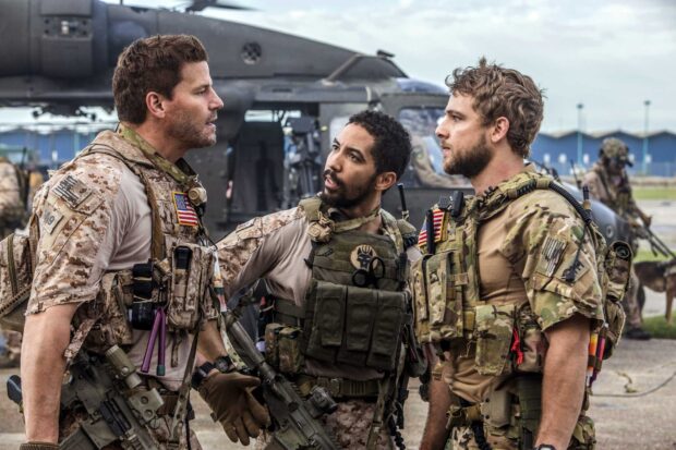 Three soldiers in tactical gear discuss in front of a helicopter in a military base, HD Desktop Wallpaper