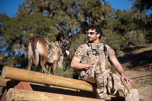 A Seal Team member sits beside a military working dog during training exercises in a forest area, HD Desktop Wallpaper