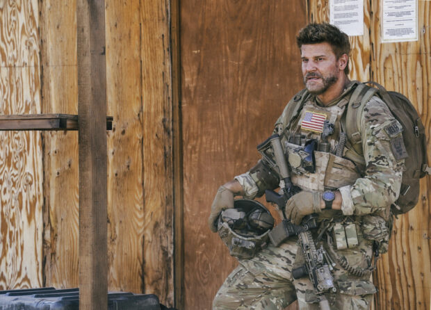 A Seal Team soldier stands ready in tactical gear holding a helmet against a wooden wall, HD Desktop Wallpaper