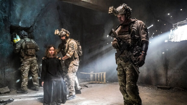 A Seal Team member comforts a captive woman while another soldier guards the area in a dark cave, HD Desktop Wallpaper