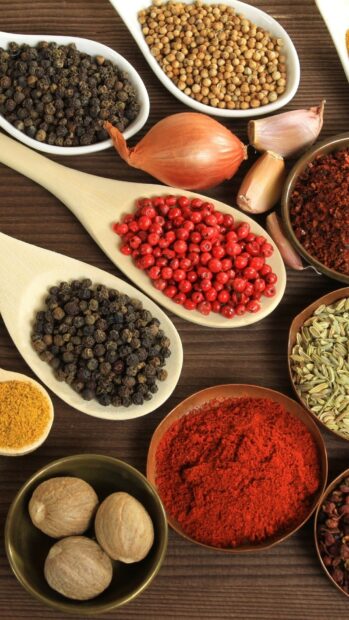 A variety of seasoning mix including peppercorns, coriander, and nutmeg on a wooden surface, HD Phone Wallpaper