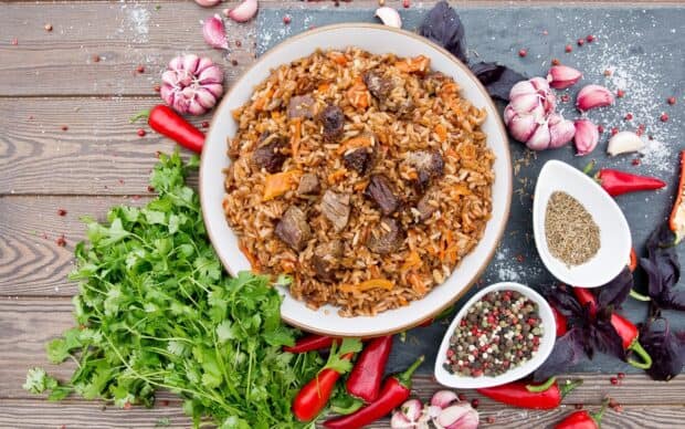 A plate of seasoned rice with meat pieces surrounded by fresh herbs and spices, HD Desktop Wallpaper