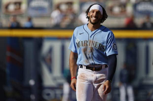 A Seattle Mariners player stands smiling on the baseball field wearing a blue jersey and white pants, 2K Desktop Wallpaper