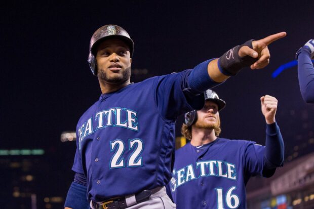 A Seattle Mariners player points while another cheers behind him during a night game, HD Desktop Wallpaper