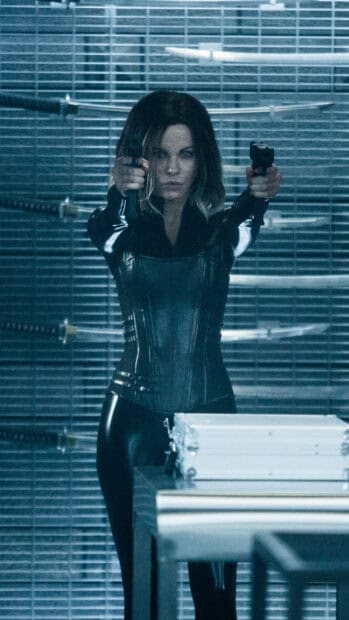Selene is holding two guns dressed in a black leather outfit with swords behind her, HD Mobile Wallpaper