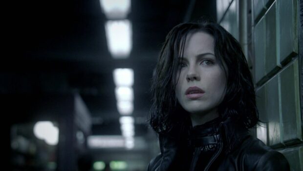 Selene stands in a dimly lit corridor wearing a black outfit with a serious expression, HD Desktop Wallpaper