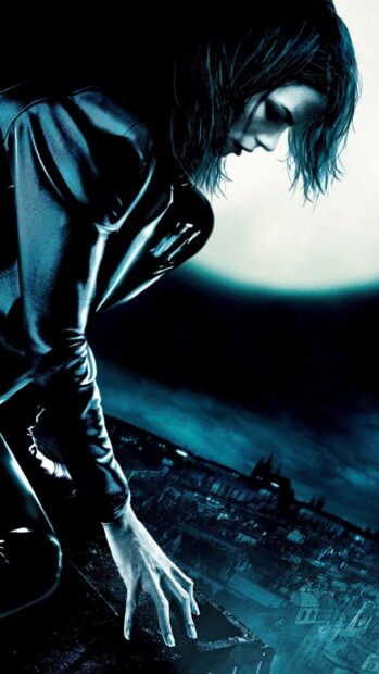 Selene crouches on a rooftop overlooking a city under a large glowing moon in Selene Underworld Wallpapers, 2K Mobile Wallpaper