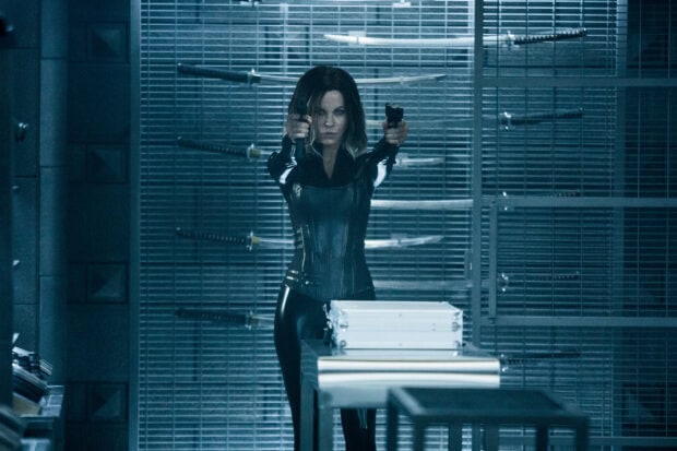 Selene from Underworld is aiming two guns in a high tech armory, 2K Desktop Wallpaper