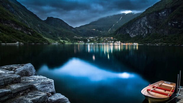A calm lake surrounded by mountains in Norwegian fjords reflects the scattered lights across the water, 4K Desktop Wallpaper