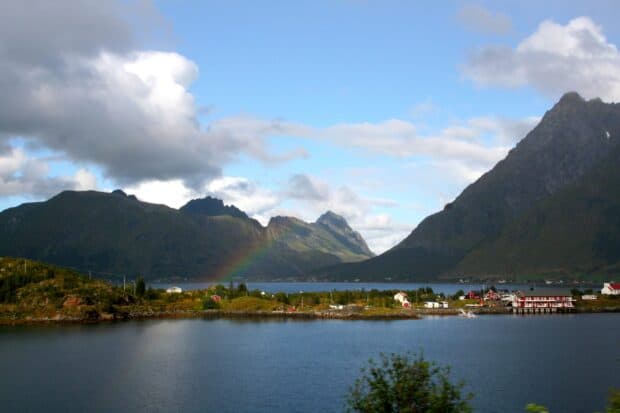 A calm view of Norwegian fjords with mountains and a rainbow under a blue sky, 2K Desktop Wallpaper