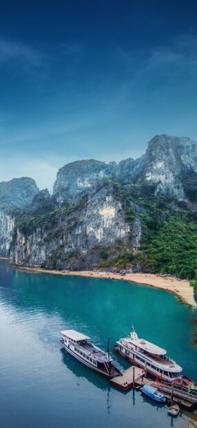 Two ferry boats docked by clear turquoise water near towering cliffs, HD Phone Wallpaper