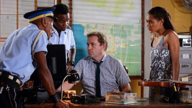 The team in Death In Paradise has a serious discussion at the police station, focusing on solving a case, HD Desktop Wallpaper
