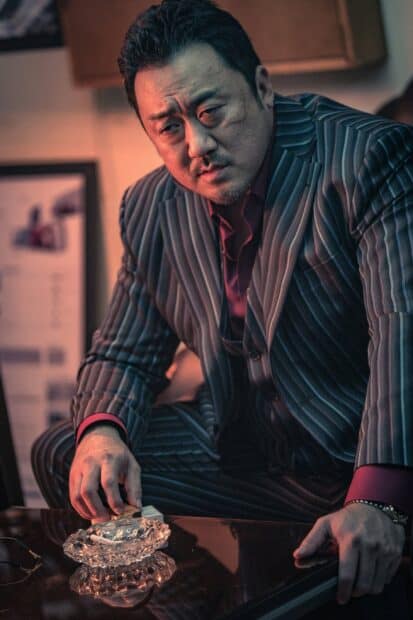 Ma Dong Seok looks thoughtful while holding a cigarette near an ashtray, 2K Mobile Wallpaper