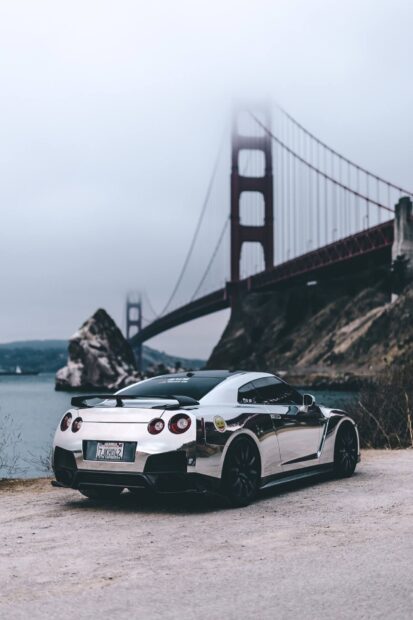 A shiny Nissan GT R is parked on a gravel path with the Golden Gate Bridge and misty sky in the background, HD Mobile Wallpaper