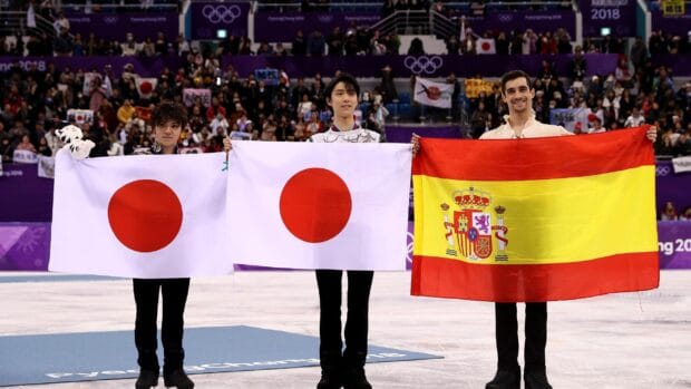 Shoma Uno celebrates with fellow medalists holding flags at the Olympic ice rink, 2K Desktop Wallpaper